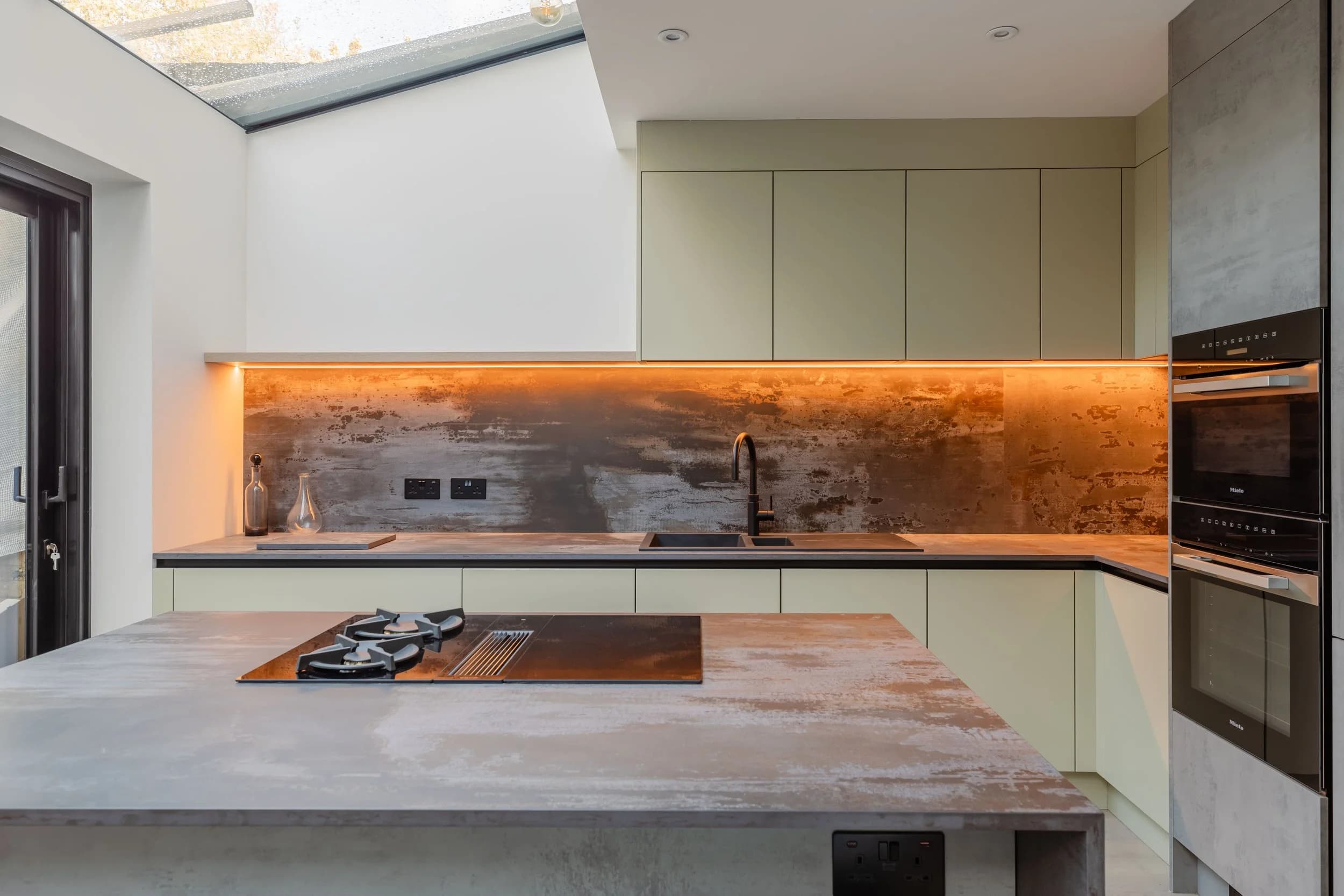 Completed Adamus and Contractors kitchen with beige cabinets, concrete backsplash and island